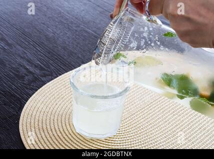 la limonade maison est versée dans le verre sur la table à partir de la verseuse en verre Banque D'Images