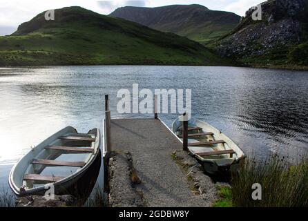 Pays de Galles, parc national de Snowdonia. Un après-midi en fin d'été. Un petit réservoir. Deux petits bateaux sur une jetée en béton. L'eau est placide et reflète t Banque D'Images