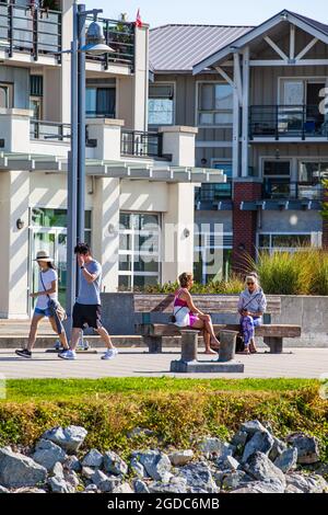 Quatre personnes se détendent le long du front de mer Steveston en Colombie-Britannique, au Canada Banque D'Images