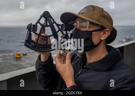 OCÉAN PACIFIQUE (janv 12, 2021) – le Quartermaster de la Marine américaine de première classe, Reyna Montue, de long Beach, en Californie, regarde à travers un stadimètre à bord du porte-avions USS Theodore Roosevelt (CVN 71) le 12 janvier 2021. Le groupe de grève des transporteurs Theodore Roosevelt est en cours de déploiement prévu dans la zone d'exploitation de la 7e flotte des États-Unis. En tant que plus grande flotte déployée en avant de la Marine américaine, avec environ 50-70 navires et sous-marins, 140 aéronefs et 20,000 marins dans la zone d'opérations à tout moment, la 7e flotte effectue des opérations navales déployées en avant à l'appui des intérêts nationaux américains Banque D'Images