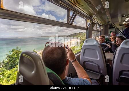 Les passagers à bord d'un train de St Ives à la baie de Carbis en admirant la vue sur la plage de Porthminster à St Ives. Cornwall, Royaume-Uni, le 6 août 2021 Banque D'Images