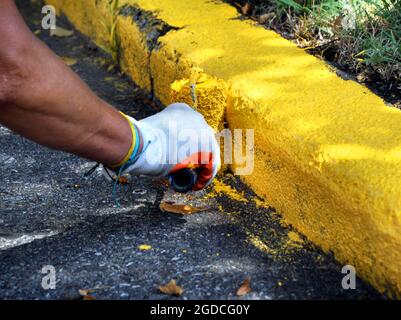 Les ouvriers repeignent le trottoir de la rue en jaune. Ils utilisent des rouleaux de peinture. Banque D'Images