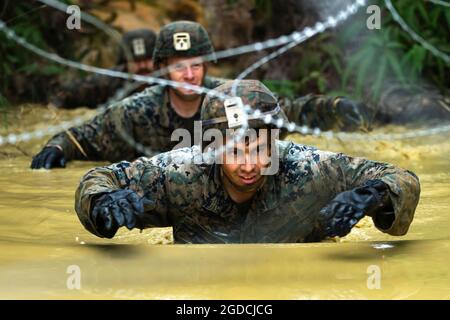 Marines des États-Unis avec 3d Marine Division, naviguez sur un obstacle aquatique tout en conduisant le cours d'endurance pendant la compétition de tir à quatre carafes de la 3d Marine Division au Camp Gonsalves, Okinawa, Japon, le 13 janvier 2021. La compétition d'une semaine teste les compétences de survie dans la jungle, les tactiques d'infanterie de base et l'excellence dans la manipulation des armes. Les participants au concours sont actuellement rattachés au 4e Régiment maritime dans le cadre du Programme de déploiement de l'unité. (É.-U. Photo du corps marin par lance Cpl. Scott AuBuchon) Banque D'Images