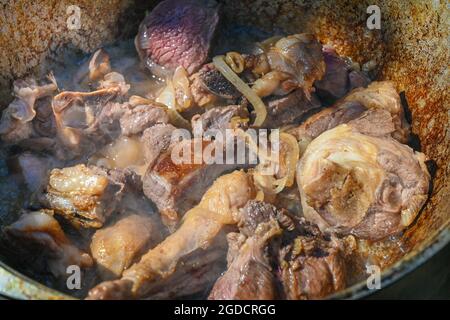 Les oignons hachés et les morceaux de viande sont frits dans de l'huile bouillante. Cuisson du pilaf dans un chou-fleur, une recette étape par étape pour le vrai pilaf. Banque D'Images