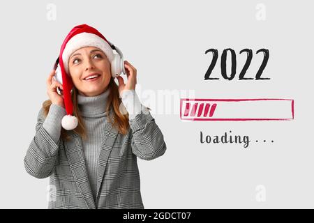 Femme mature avec casque et chapeau du Père Noël sur fond gris. Concept des objectifs de la nouvelle année Banque D'Images