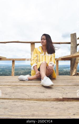 Femme asiatique assise sur une plate-forme en bois contre les chaînes de montagnes Banque D'Images