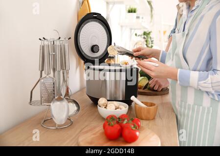 Femme utilisant une cuisinière multiple dans la cuisine Banque D'Images