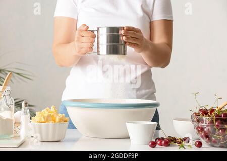 Femme préparant de la pâte pour la tarte aux cerises à la table Banque D'Images