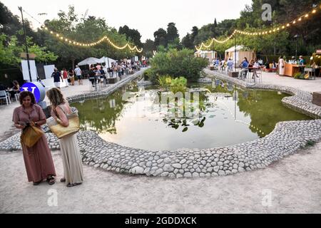 Sitges, Espagne. 13 août 2021. Les gens sont vus dans le quartier du village de gastro du Festival Jardins de Terramar à Sitges. Chaque année, la ville de Sitges (Barcelone, Espagne) accueille le Festival des Jardins de Terramar où des chanteurs internationaux se produisent en direct. Des heures avant chaque concert, les visiteurs peuvent déguster une cuisine méditerranéenne, des vins et des cavas (champagne de la région de Catalogne) au gastro Village dans une atmosphère détendue dans sa région de Chill Out. Des spectacles musicaux sont organisés pour divertir le public. Crédit : SOPA Images Limited/Alamy Live News Banque D'Images