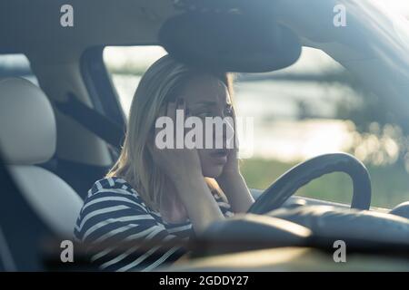 Femme effrayée assis au siège du conducteur dans la voiture peur de conduire. Véhicule de conduite féminin d'âge moyen anxieux Banque D'Images