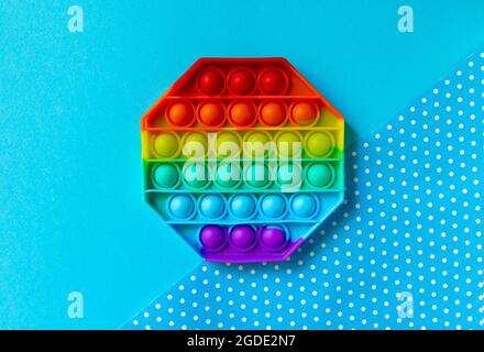 Un jouet tendance populaire, le jouet, le pousser, le pop-it sur fond bleu Banque D'Images