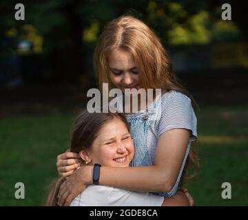 Une petite fille embrasse sa sœur aînée. Amour et amitié. Concept de famille heureux. Banque D'Images