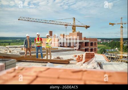 Constructeurs de casques de chantier conversant avec un ingénieur sur le chantier de construction Banque D'Images