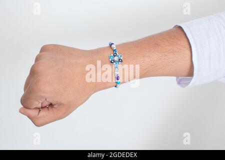 Main portant beau bleu diamant design rakhi à l'occasion de raksha bandhan sur fond blanc. Festival indien célébré en Inde à expre Banque D'Images