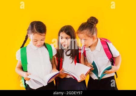 Les petites écolières lisent les livres sur fond jaune Banque D'Images