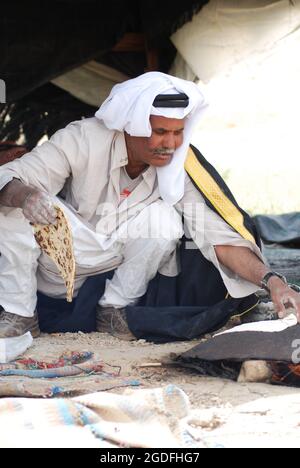 MITZPE RAMON, ISRAËL - 08 avril 2008 : Bédouin dans le désert du Néguev en Israël, cuisine traditionnelle de pain dans une tente, père et fils mangeant un bedo typique Banque D'Images