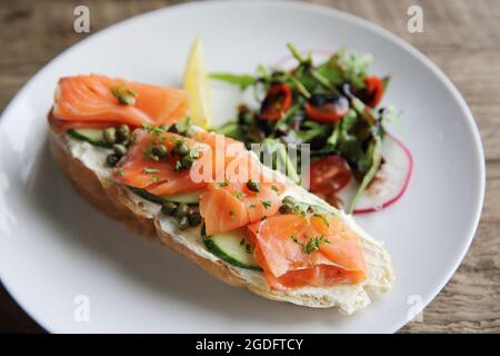 saumon fumé sur pain grillé, crème fraîche, citron et salade Banque D'Images