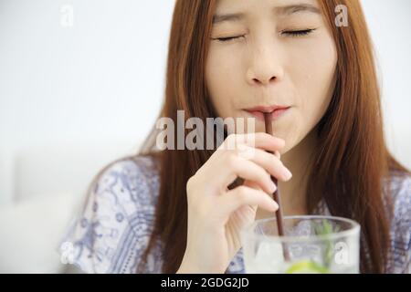 femme buvant du jus de citron vert dans un café blanc Banque D'Images