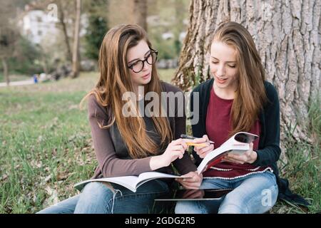 Amies reading book in park Banque D'Images