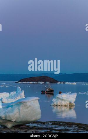 Petit bateau amarré parmi de grands morceaux de glace de mer Banque D'Images