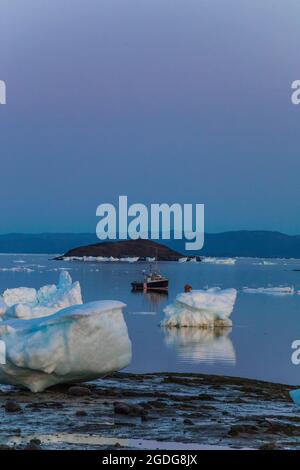 Petit bateau amarré parmi de grands morceaux de glace de mer Banque D'Images