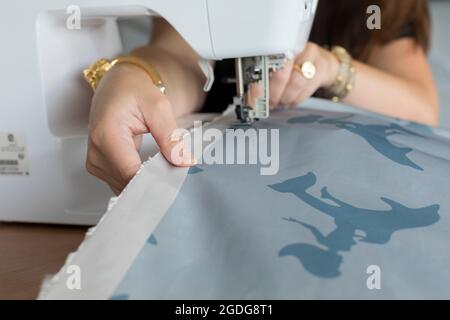 Gros plan des mains de femme tissu de couture avec machine à coudre électrique Banque D'Images