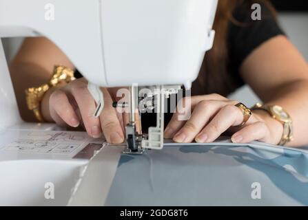 Gros plan des mains de femme tissu de couture avec machine à coudre électrique Banque D'Images