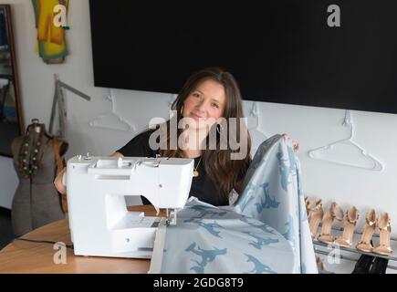 L'entrepreneur de mode féminine rasse le tissu sur la machine à coudre électrique Banque D'Images