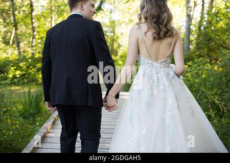 Vue arrière d'un couple bien habillé tenant les mains à l'extérieur. Banque D'Images