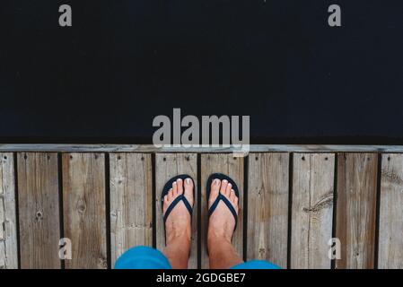 Au-dessus des pieds de la femme dans les tongs debout sur le bord du quai. Banque D'Images