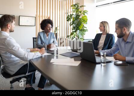 employés de bureau assis à table et écoutant le leader noir pendant la conférence Banque D'Images