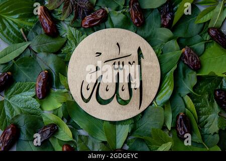 Nom d'Allah en arabe sur bois d'or, feuilles vertes et dattes fond de fruit. La calligraphie signifie le Dieu Al Mighty de l'Islam religion. Banque D'Images