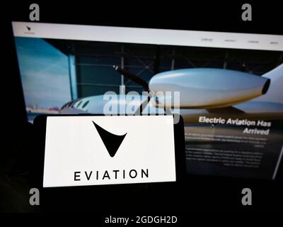 Personne tenant un smartphone avec le logo de la compagnie d'avions électriques Eviation Aircraft Ltd. À l'écran devant le site Web. Mise au point sur l'affichage du téléphone. Banque D'Images