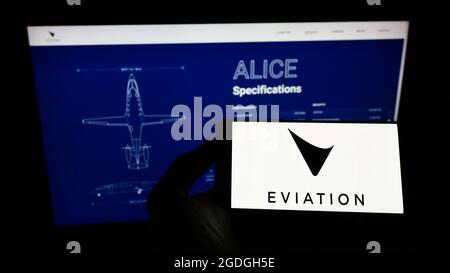 Personne tenant un téléphone cellulaire avec le logo de la compagnie d'avions électriques Eviation Aircraft Ltd. À l'écran devant le site Web. Mise au point sur l'affichage du téléphone. Banque D'Images