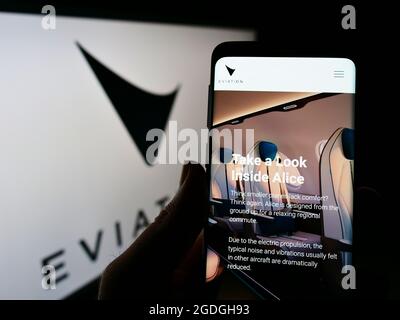 Personne tenant un smartphone avec la page Web de la compagnie d'avions électriques Eviation Aircraft Ltd. À l'écran avec le logo. Concentrez-vous sur le centre de l'écran du téléphone. Banque D'Images