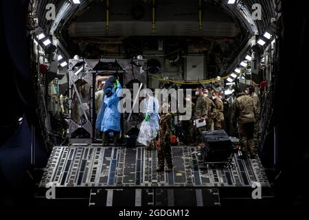 Les aviateurs se préparent à décharger les patients COVID-19 lors de la première utilisation opérationnelle du système d'isolation de transport de la base aérienne de Ramstein, en Allemagne, le 10 avril 2020. Le TIS est une unité de confinement des maladies infectieuses conçue pour minimiser le risque de contamination pour les membres de l'équipage et les agents médicaux, tout en permettant des soins médicaux en vol pour les patients atteints d'une maladie. (É.-U. Photo de la Force aérienne par le sergent d'état-major. Devin Nothstine) Banque D'Images