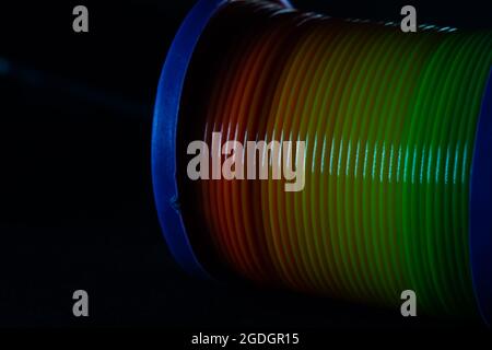 Gros plan d'un jouet de printemps arc-en-ciel slinky sur fond noir Banque D'Images