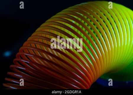 Gros plan d'un jouet de printemps arc-en-ciel slinky sur fond noir Banque D'Images