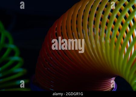 Gros plan d'un jouet de printemps arc-en-ciel slinky sur fond noir Banque D'Images