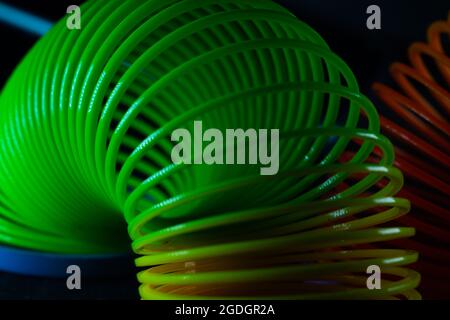 Gros plan d'un jouet de printemps arc-en-ciel slinky sur fond noir Banque D'Images