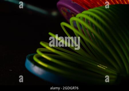 Gros plan d'un jouet de printemps arc-en-ciel slinky sur fond noir Banque D'Images