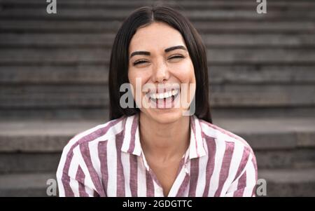 Bonne femme latine souriant dans la caméra tout en étant assise dans les escaliers urbains Banque D'Images