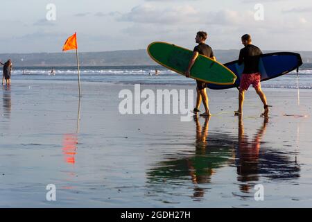 Kuta, Indonésie - 14 septembre 2018 : surfeurs au coucher du soleil sur la plage de Seminyak à Bali. C'est l'une des attractions touristiques dans ce domaine. Banque D'Images