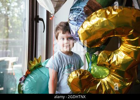 Joyeux garçon d'anniversaire se tient près de la fenêtre Banque D'Images