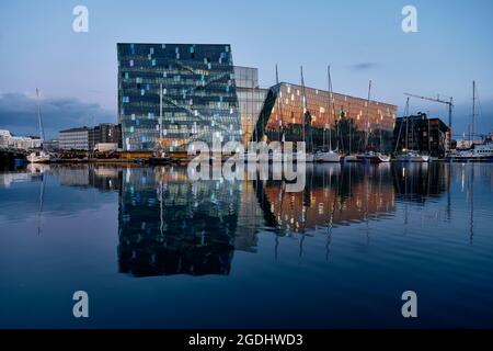 Eau de mer calme reflétant des bâtiments modernes en verre et des yachts en soirée dans le port de la ville en Islande Banque D'Images