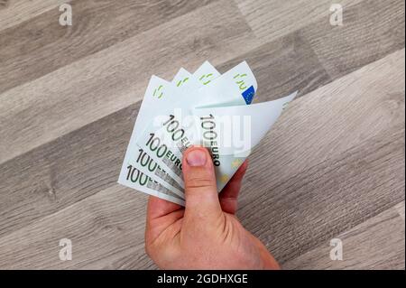 main d'homme comptant 100 billets en euros sur une table en bois Banque D'Images