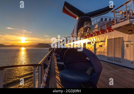 Alaska, Etats-Unis - 22 juin 2018 : Carnaval Légende voile au coucher du soleil dans l'un des Fjords d'Alaska. Coucher de soleil et montagnes en arrière-plan. Vue f Banque D'Images