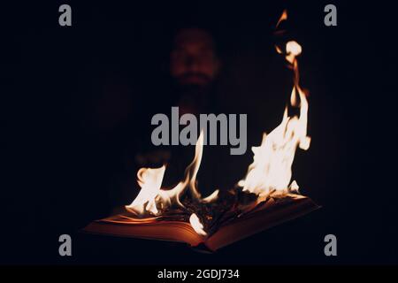 L'homme tient le livre brûlant dans ses mains Banque D'Images