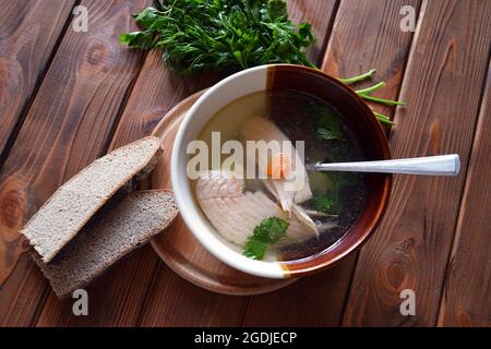 Soupe chaude de saumon avec carottes, persil vert, aneth et pain de seigle sur la table en bois Banque D'Images