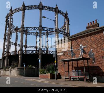 Gasometer ou Gas Holder, construit en fonte et en acier, œuvres d'art Banksy au-dessus d'un abri d'autobus à Admiralty Road, Great Yarmouth, Norfolk, Angleterre, Royaume-Uni Banque D'Images